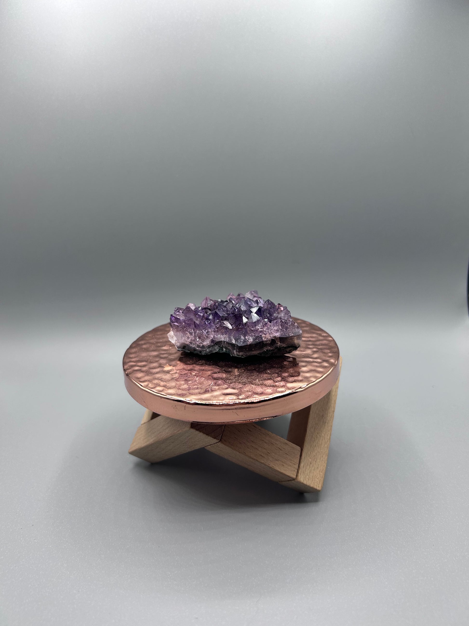 raw amethyst cluster posed inside on a copper plate.