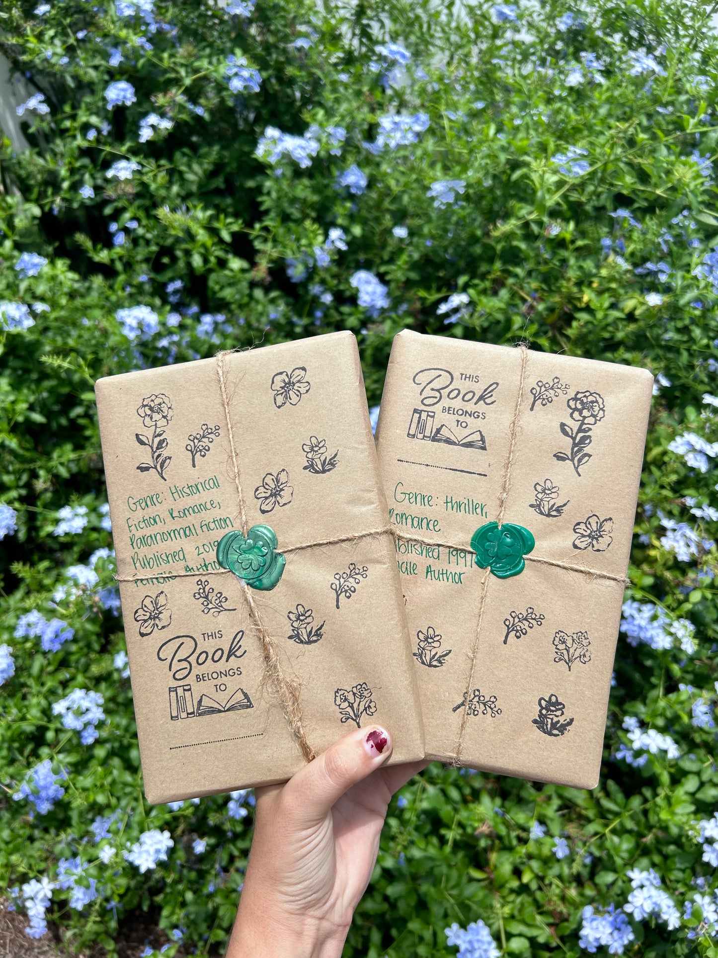 blind date with a book. two books covered with kraft paper with floral stamps, wrapped in twine with a green clover wax stamp to seal.