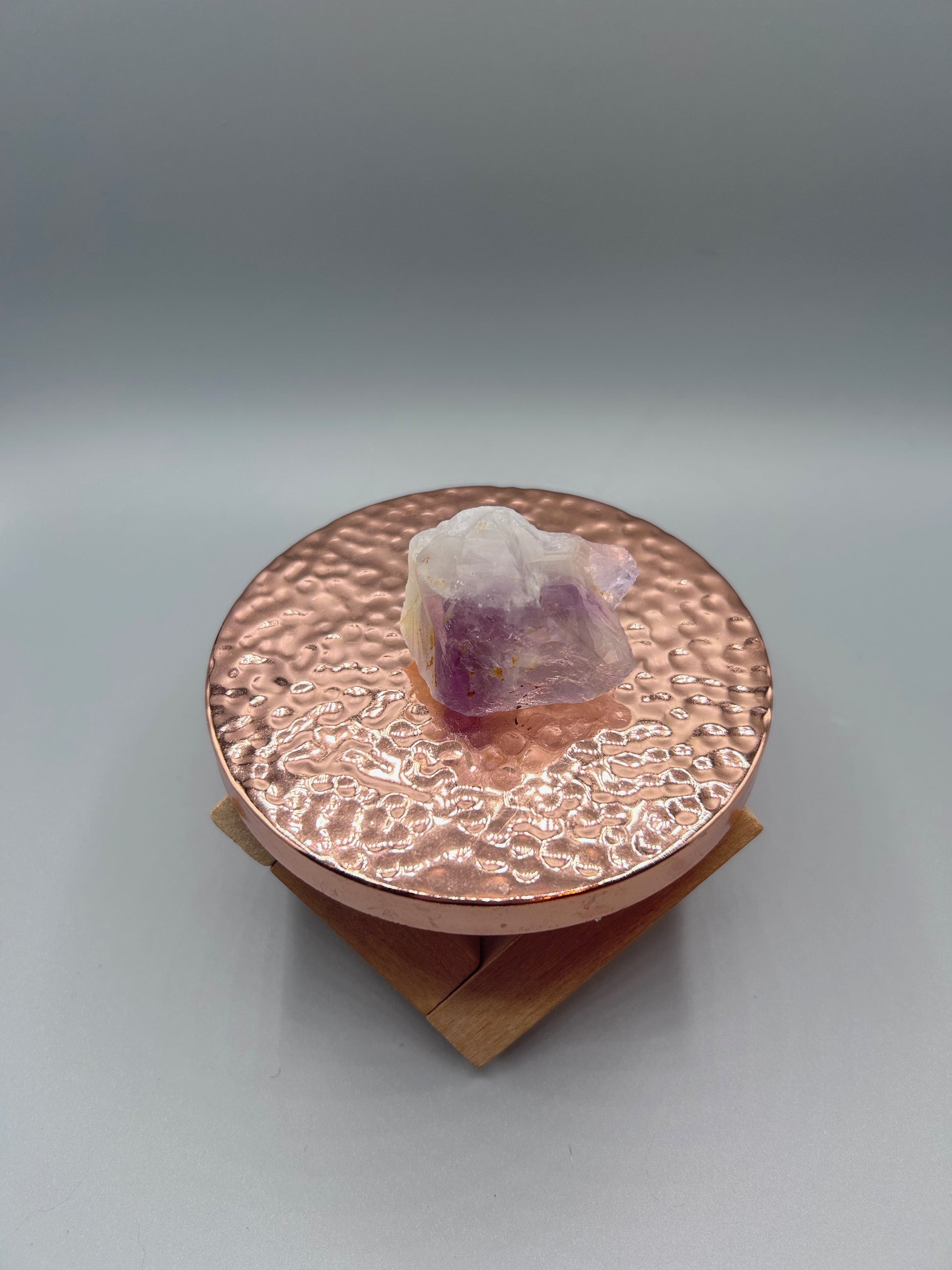 raw amethyst crystal posed inside on copper plate.